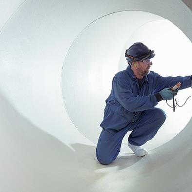 man in blue coveralls crouching inside large white turbine hall