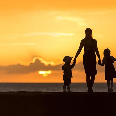 silhouette of woman and two children holding hands at sunset